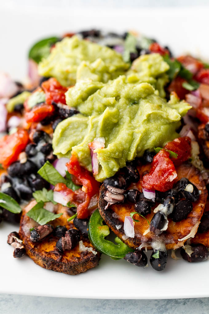 Loaded Sweet Potato Nachos - seasoned baked rounds topped with black beans, jalapeños, onions, cheese, salsa, and guacamole for an easy vegetarian, Mexican-inspired meal that's way healthier than traditional nachos | runningwithspoons.com