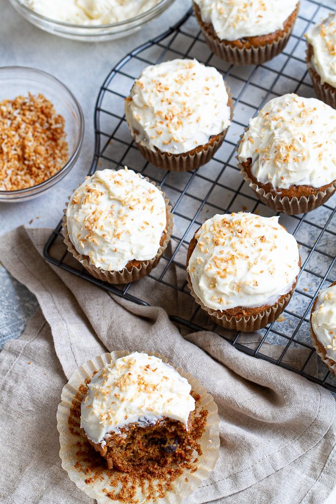 Flourless carrot cake muffins with frosting on a cooling tray.