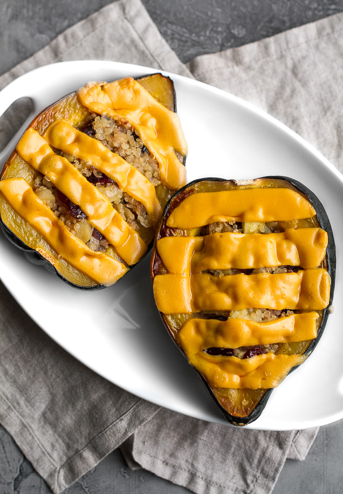 This cheezy apple cranberry quinoa stuffed squash is packed with sweet & savoury flavours and topped with an ooey, gooey, dairy-free cheese. It's healthy plant-based comfort food at its finest! | runningwithspoons.com