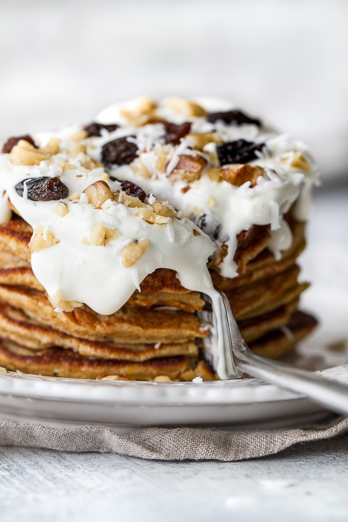 These light and fluffy Carrot Cake Greek Yogurt Pancakes are sure to keep you satisfied all morning with over 20g of whole food protein! They’re gluten-free thanks to the oats and whipped up in the blender in under 5 minutes! | runningwithspoons.com