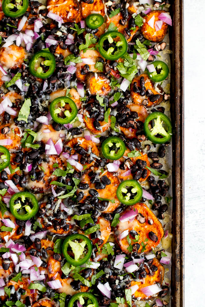 Loaded Sweet Potato Nachos - seasoned baked rounds topped with black beans, jalapeños, onions, cheese, salsa, and guacamole for an easy vegetarian, Mexican-inspired meal that's way healthier than traditional nachos | runningwithspoons.com