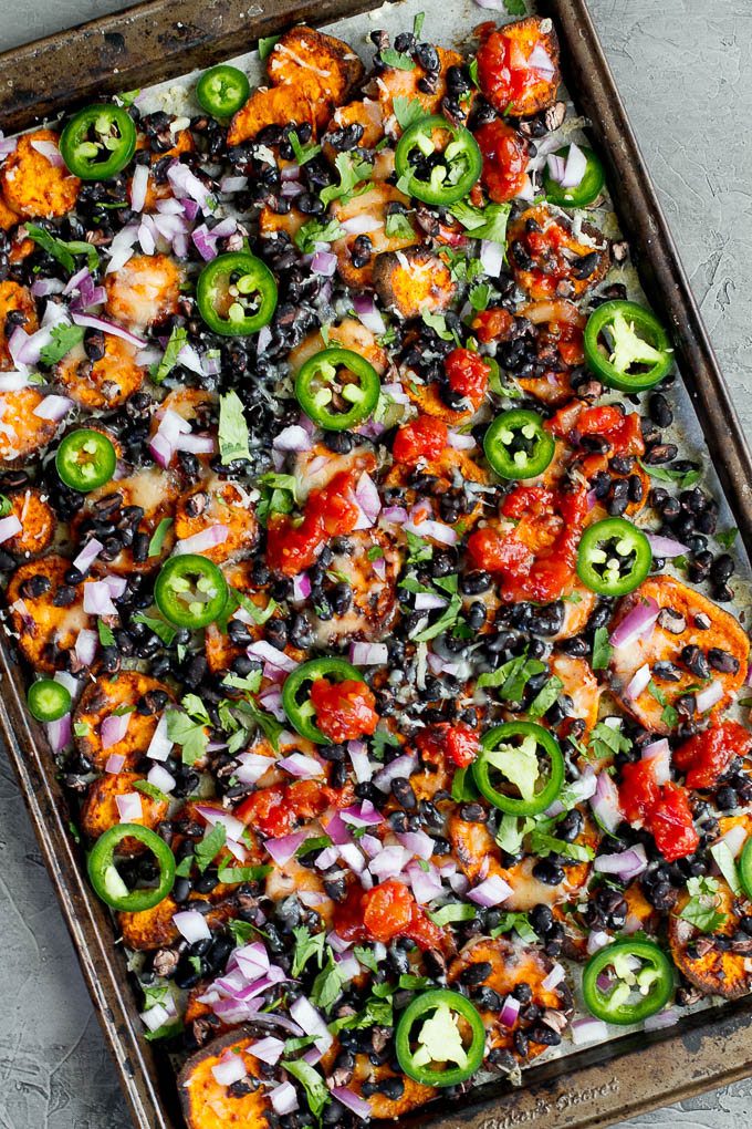 Loaded Sweet Potato Nachos - seasoned baked rounds topped with black beans, jalapeños, onions, cheese, salsa, and guacamole for an easy vegetarian, Mexican-inspired meal that's way healthier than traditional nachos | runningwithspoons.com