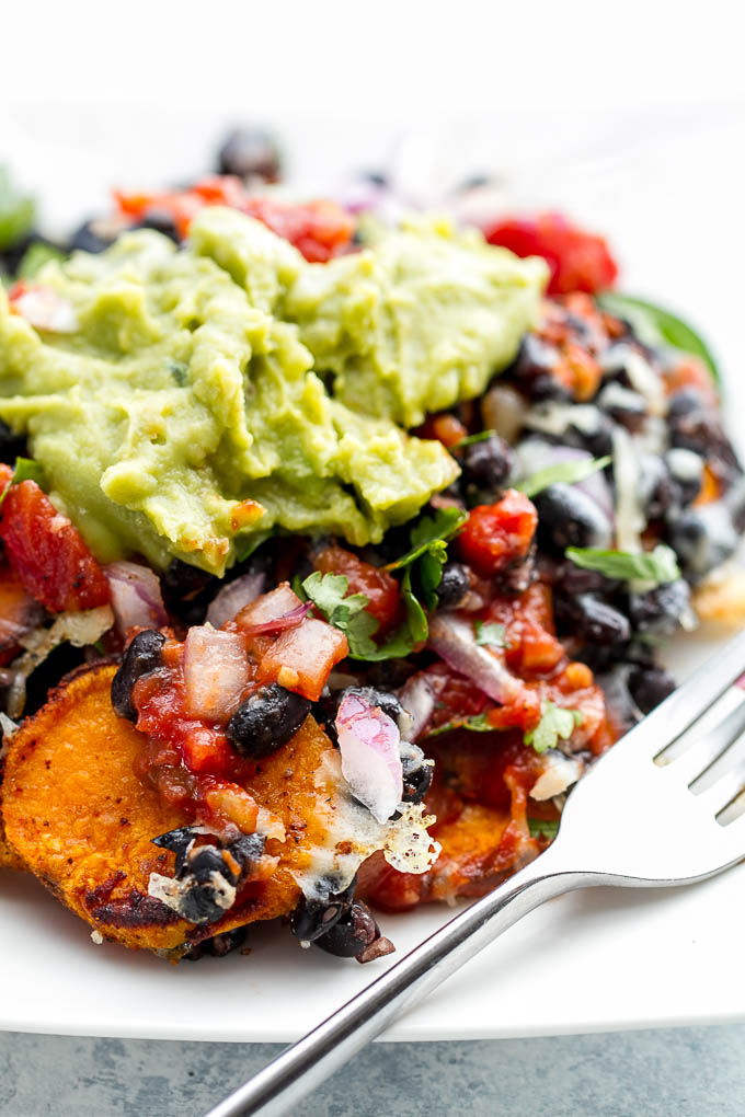 Loaded Sweet Potato Nachos - seasoned baked rounds topped with black beans, jalapeños, onions, cheese, salsa, and guacamole for an easy vegetarian, Mexican-inspired meal that's way healthier than traditional nachos | runningwithspoons.com