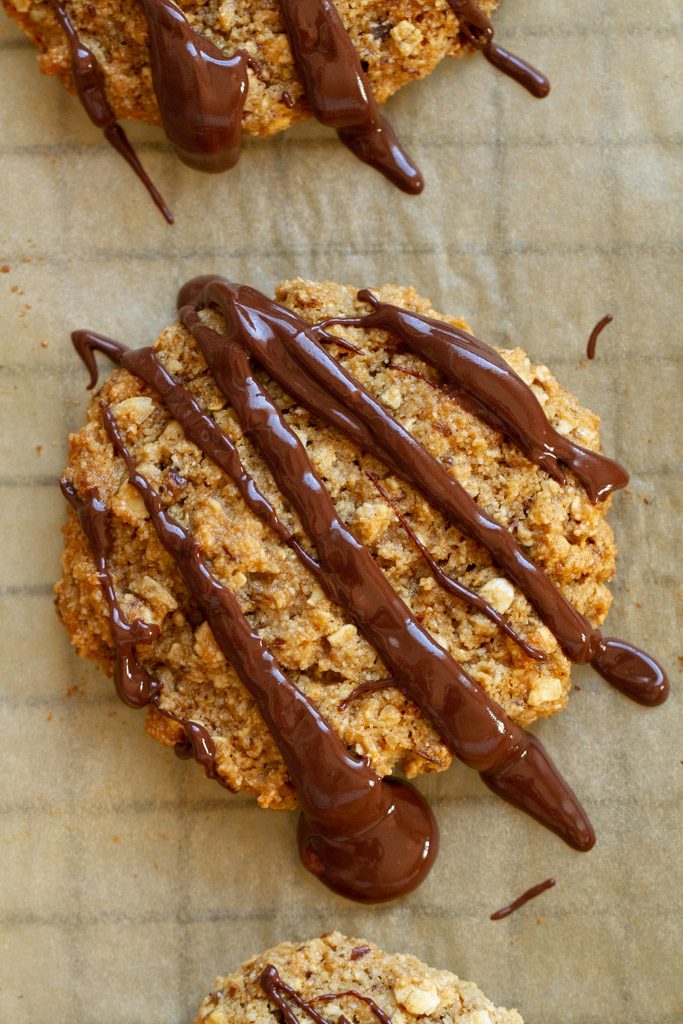 A close up soft and chewy oatmeal cookie drizzled in chocolate.