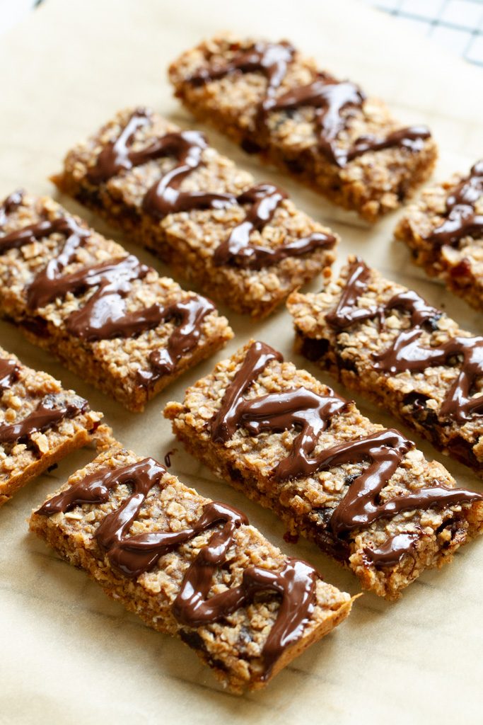 Soft and chewy granola bars cut into squares and drizzled with chocolate.