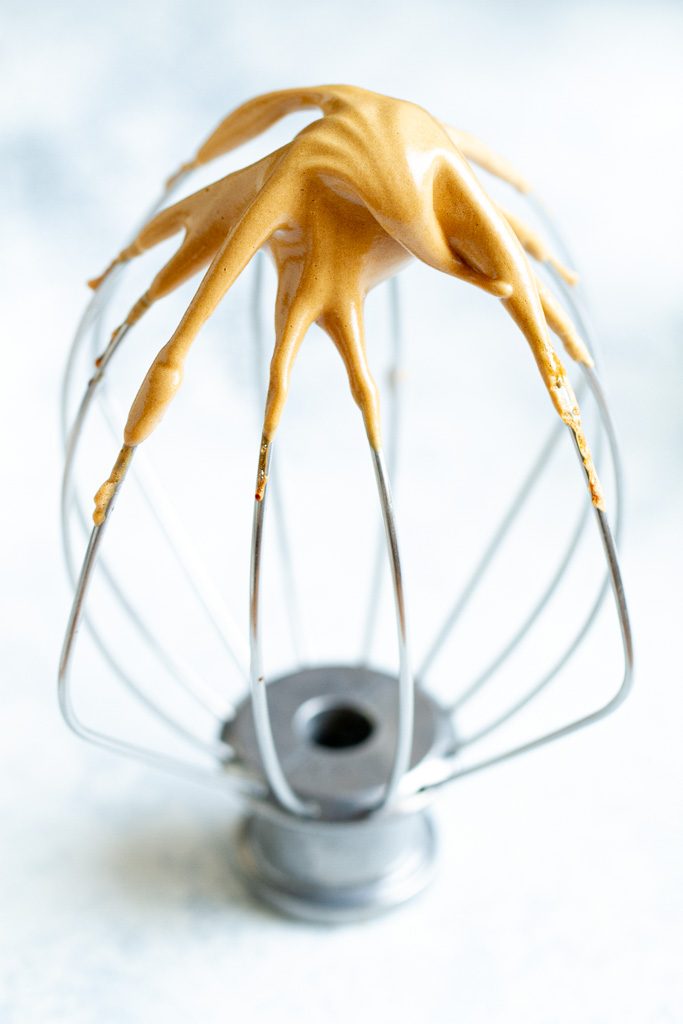 A little bit of coffee foam on the tip of a whisk.