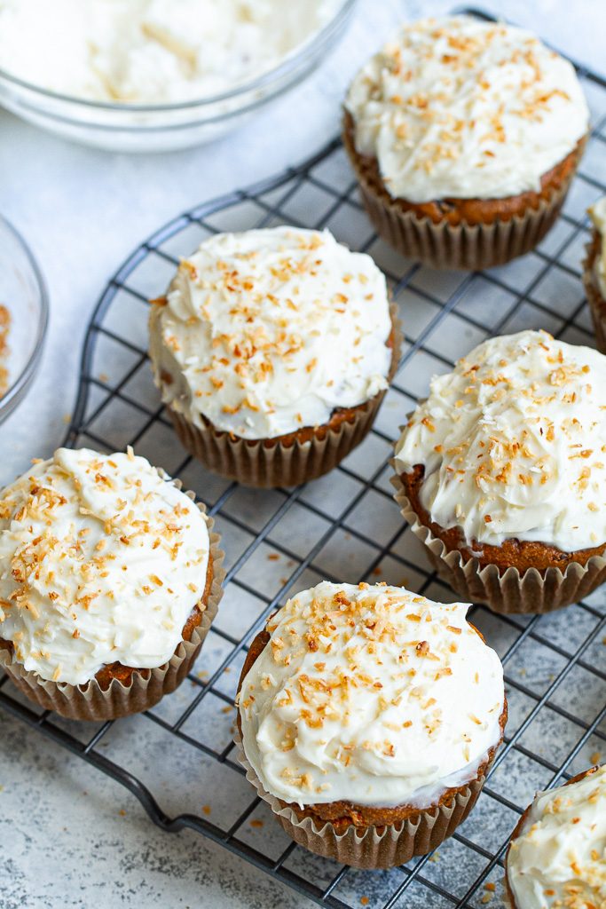 Flourless carrot cake muffins with cream cheese frosting sitting on a cooling tray.