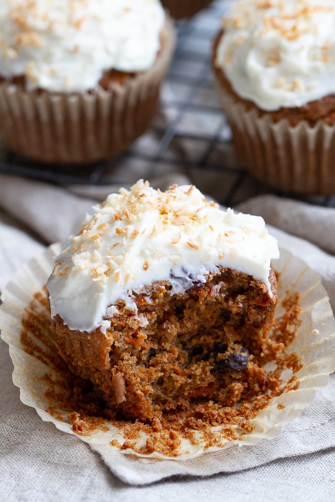 A flourless carrot cake muffin with a bite taken out of it.