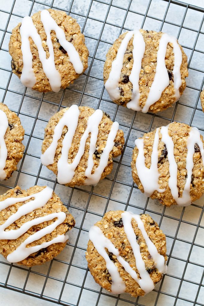 A top view of flourless oatmeal raisin cookies with icing sitting on a cooling rack.