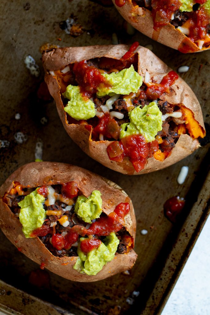 Taco stuffed sweet potatoes topped with avocado and salsa.