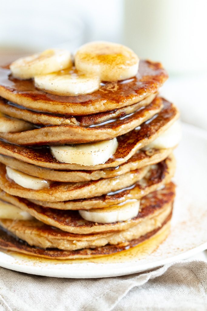 A stack of easy banana oat pancakes topped with maple syrup.