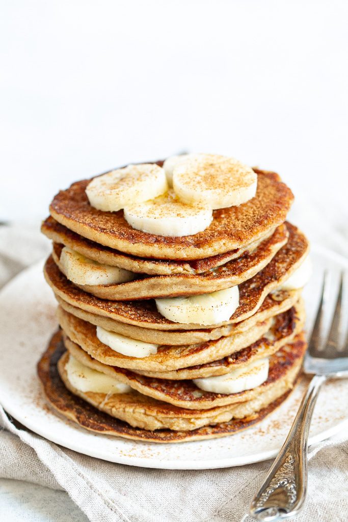 A stack of easy banana oat pancakes layered with slices of banana.