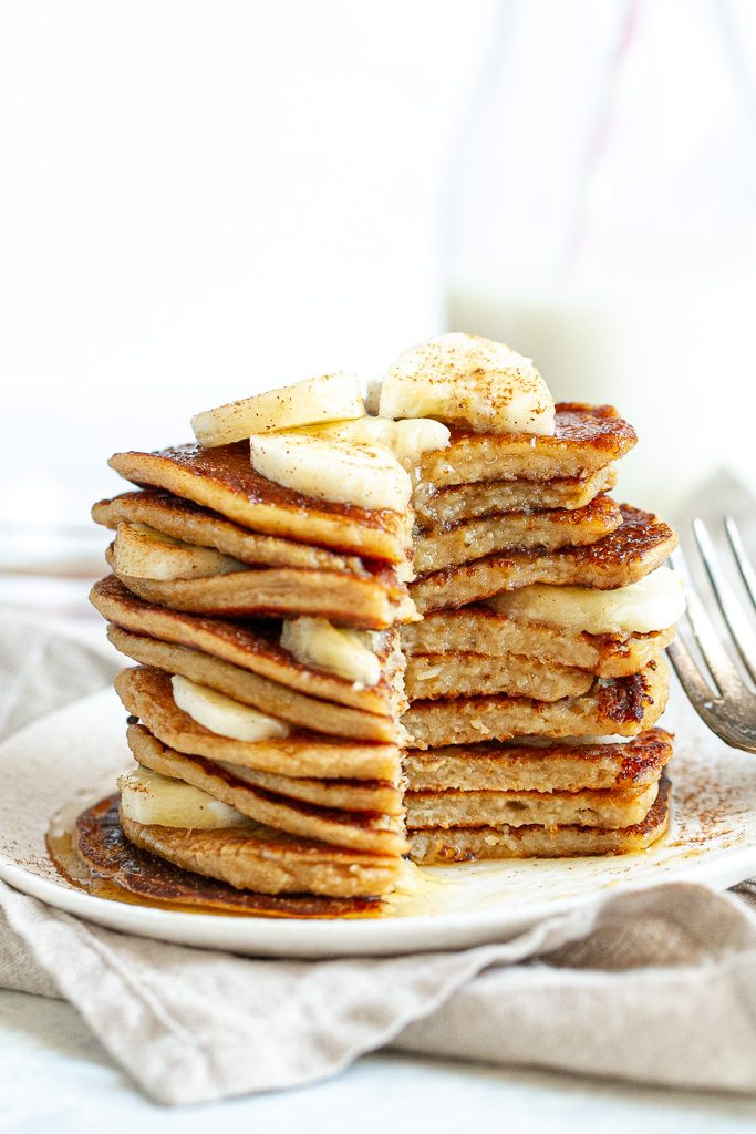 A stack of easy banana oat pancakes topped with maple syrup.