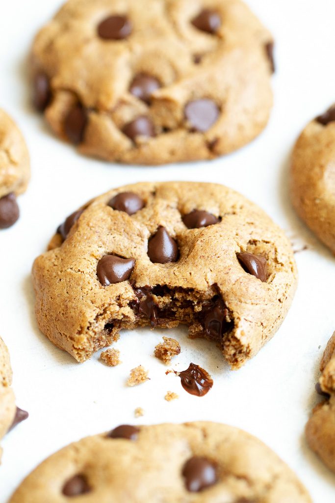 A flourless chocolate chip cookie with a bite taken out of it.