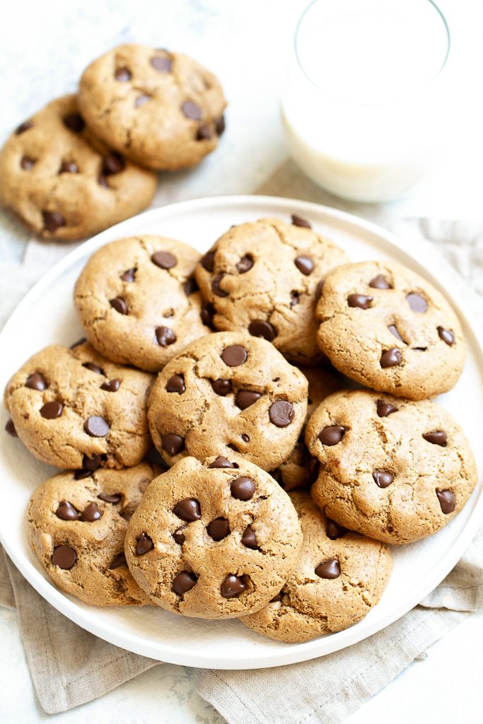 A plate of flourless chocolate chip cookies with a glass of milk.