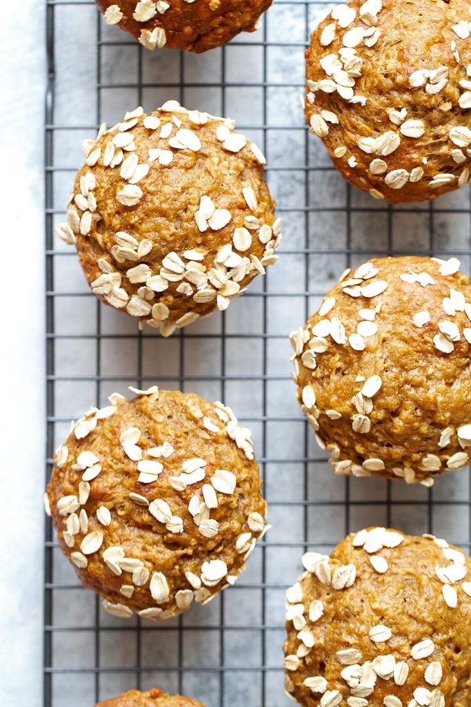 A top view of banana oat muffins on a cooling rack with oat flaked on top of the muffins.